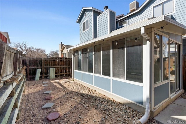 view of side of home with a fenced backyard and a sunroom