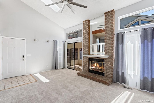 unfurnished living room with visible vents, high vaulted ceiling, a ceiling fan, carpet, and a fireplace