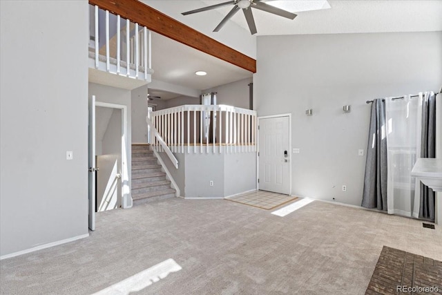 unfurnished living room with beamed ceiling, high vaulted ceiling, carpet, and a ceiling fan