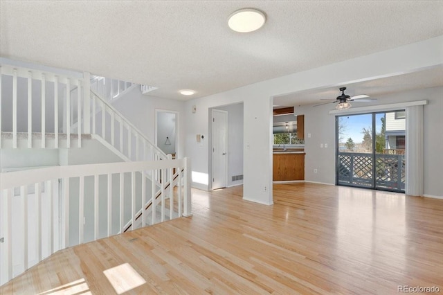 empty room featuring a textured ceiling, a ceiling fan, baseboards, and wood finished floors