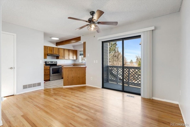 kitchen with visible vents, under cabinet range hood, brown cabinets, stainless steel range with electric cooktop, and light wood-style flooring