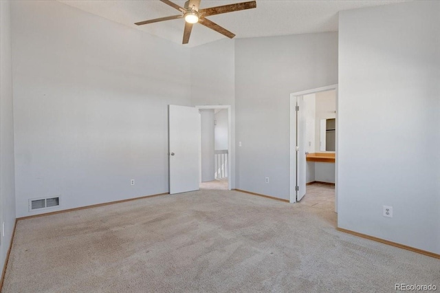 unfurnished bedroom featuring visible vents, connected bathroom, baseboards, carpet flooring, and a towering ceiling