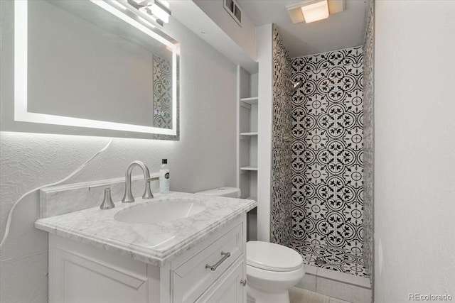 full bathroom featuring visible vents, toilet, a stall shower, vanity, and a textured wall