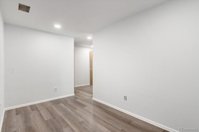 empty room featuring recessed lighting, wood finished floors, and baseboards