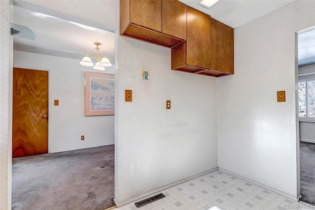 kitchen with pendant lighting, light colored carpet, and an inviting chandelier