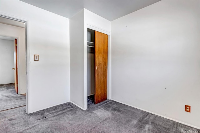 unfurnished bedroom featuring dark carpet and a closet