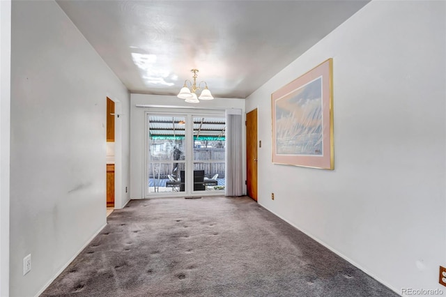 empty room featuring a notable chandelier and carpet floors