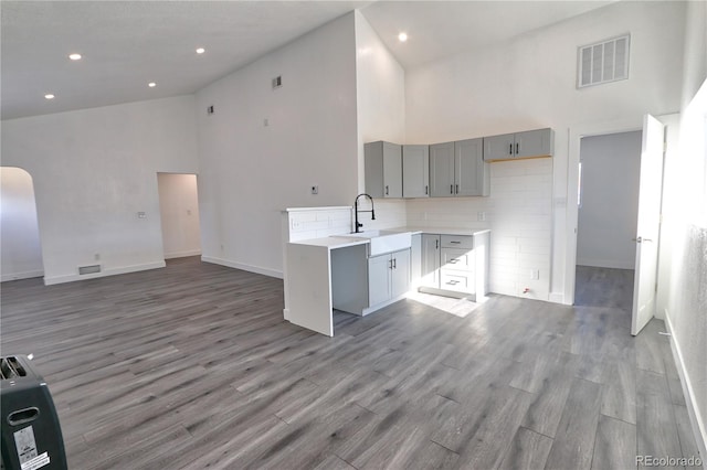 kitchen featuring gray cabinets, light hardwood / wood-style flooring, a towering ceiling, and sink