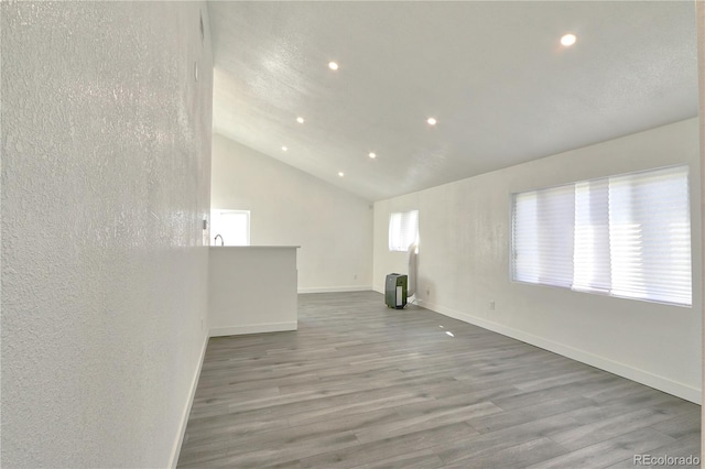 spare room with light wood-type flooring and vaulted ceiling