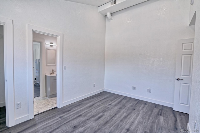 unfurnished bedroom with connected bathroom, dark wood-type flooring, and sink