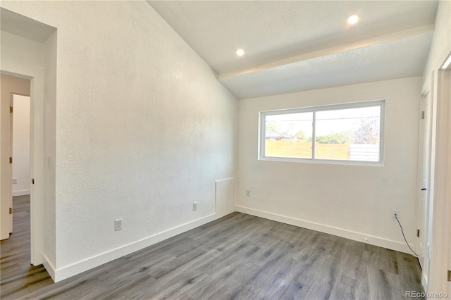 spare room with hardwood / wood-style floors and vaulted ceiling