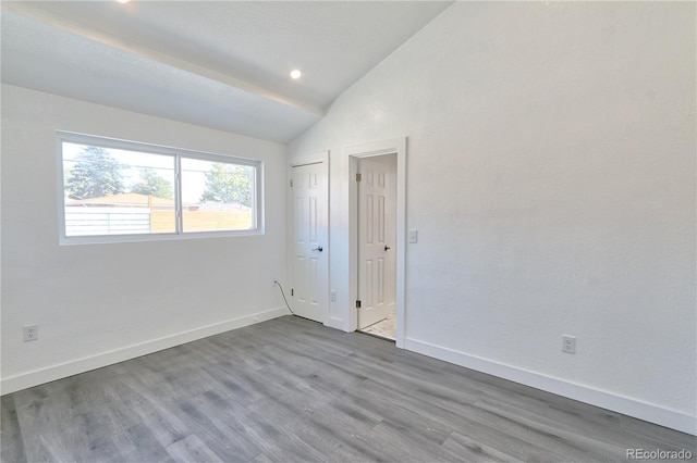 spare room featuring light hardwood / wood-style floors and lofted ceiling