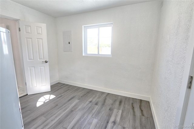 unfurnished room featuring light wood-type flooring and electric panel