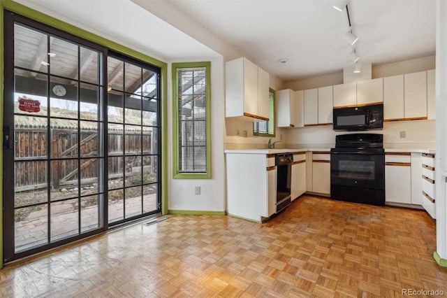 kitchen with white cabinets, sink, light parquet flooring, and black appliances