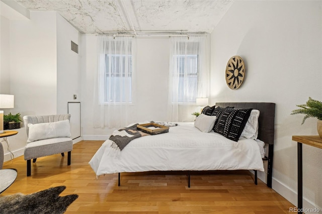 bedroom with visible vents, baseboards, and wood finished floors