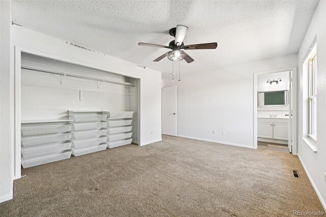 920 44th Avenue Ct Unit 30, Greeley, CO 80634 - unfurnished bedroom with carpet flooring, a textured ceiling, a closet, a ceiling fan, and connected bathroom