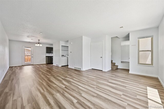 920 44th Avenue Ct Unit 30, Greeley, CO 80634 - unfurnished living room featuring a textured ceiling, light wood-type flooring, stairs, and a chandelier