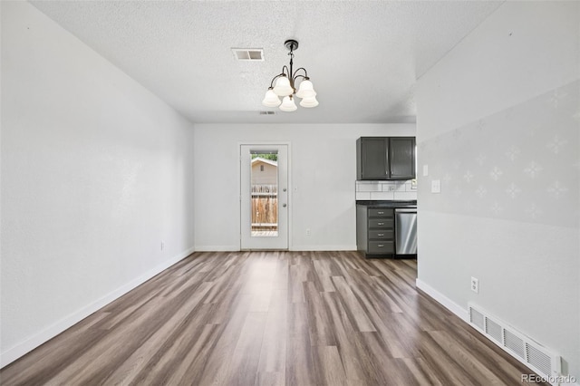 920 44th Avenue Ct Unit 30, Greeley, CO 80634 - unfurnished dining area featuring wood finished floors, a chandelier, and a textured ceiling