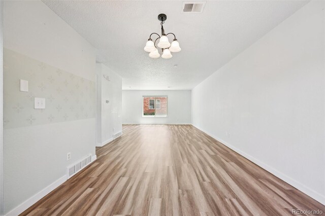 920 44th Avenue Ct Unit 30, Greeley, CO 80634 - unfurnished living room featuring wood finished floors, a chandelier, and a textured ceiling