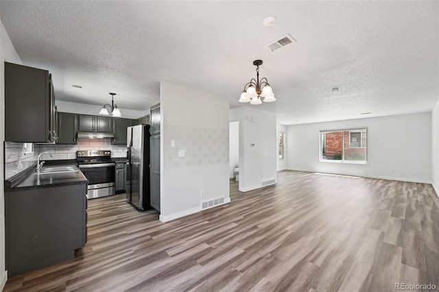 920 44th Avenue Ct Unit 30, Greeley, CO 80634 - kitchen featuring appliances with stainless steel finishes, a chandelier, open floor plan, a textured ceiling, and under cabinet range hood
