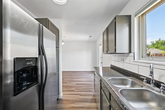 920 44th Avenue Ct Unit 30, Greeley, CO 80634 - kitchen featuring stainless steel appliances, dark countertops, wood finished floors, a textured ceiling, and tasteful backsplash