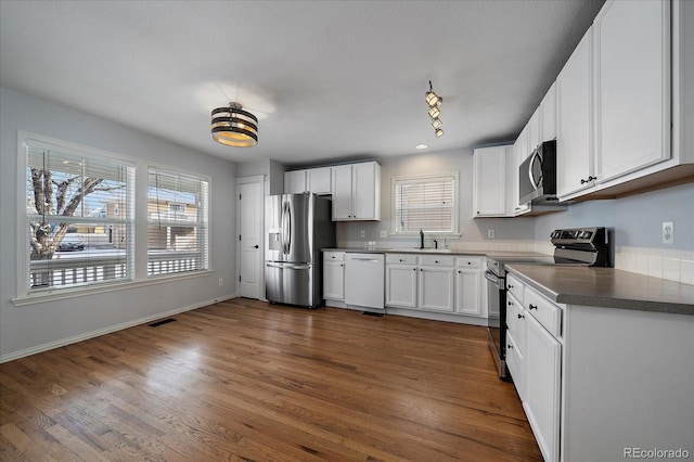 kitchen with dark hardwood / wood-style floors, sink, white cabinetry, and stainless steel appliances