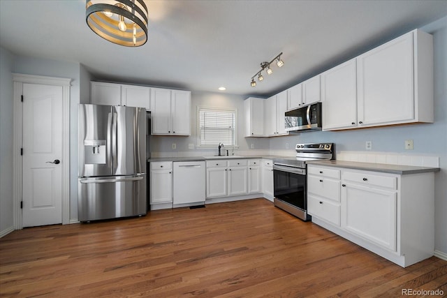 kitchen with white cabinetry, dark wood-type flooring, stainless steel appliances, and sink