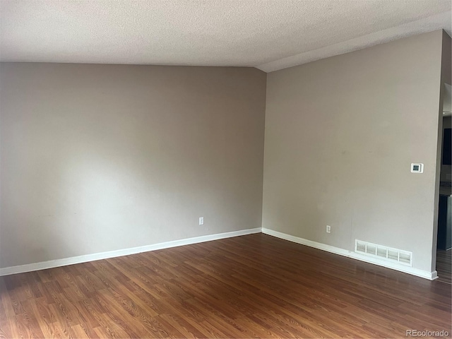 spare room with lofted ceiling, a textured ceiling, and dark hardwood / wood-style flooring