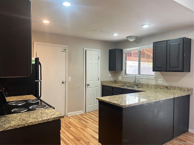 kitchen featuring black range with electric cooktop, sink, light wood-type flooring, and light stone counters