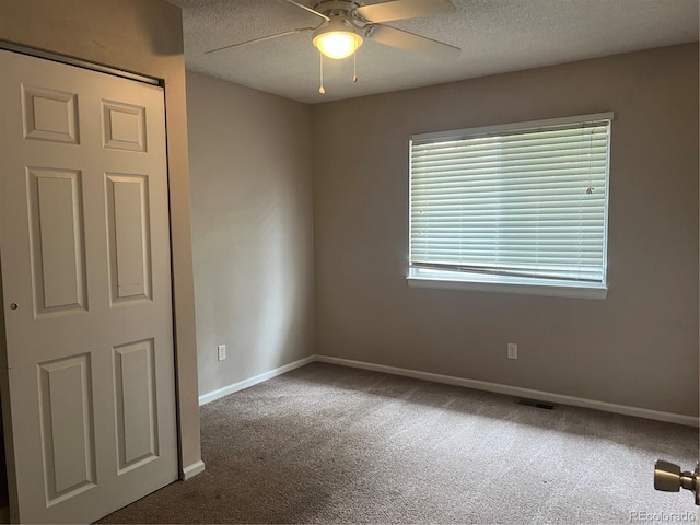 carpeted spare room with ceiling fan and a textured ceiling