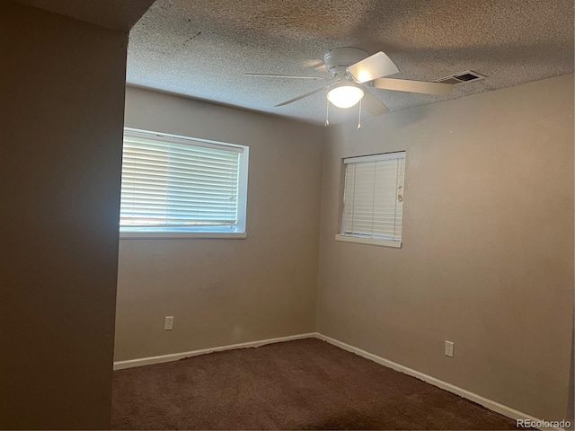 empty room featuring a textured ceiling, dark colored carpet, and ceiling fan