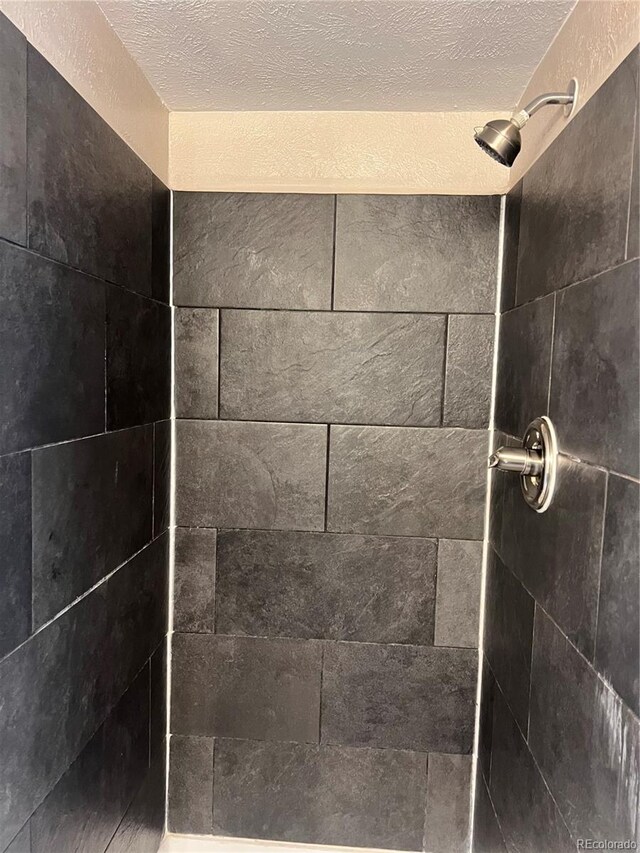 interior details featuring a textured ceiling and a tile shower