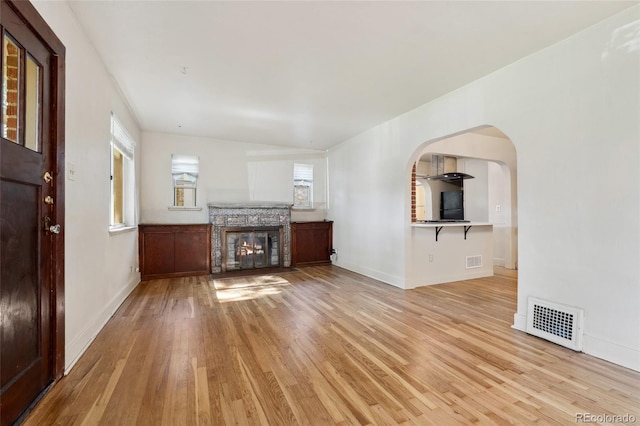 521 Harrison St, Denver, CO 80206 - unfurnished living room with light wood finished floors, a fireplace, and arched walkways