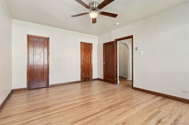 521 Harrison St, Denver, CO 80206 - unfurnished bedroom with light wood-style floors, arched walkways, a ceiling fan, and two closets