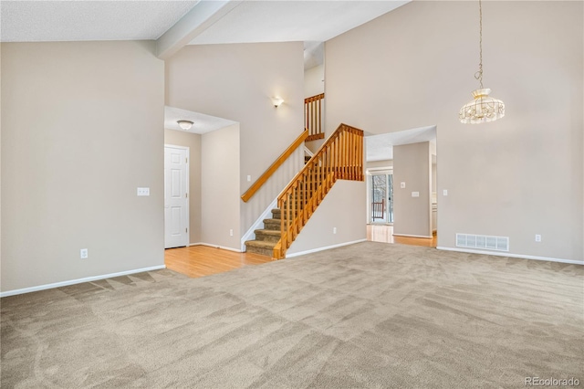 unfurnished living room featuring a chandelier, light carpet, and high vaulted ceiling