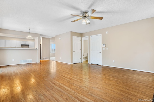 unfurnished living room featuring ceiling fan, light hardwood / wood-style floors, and a textured ceiling