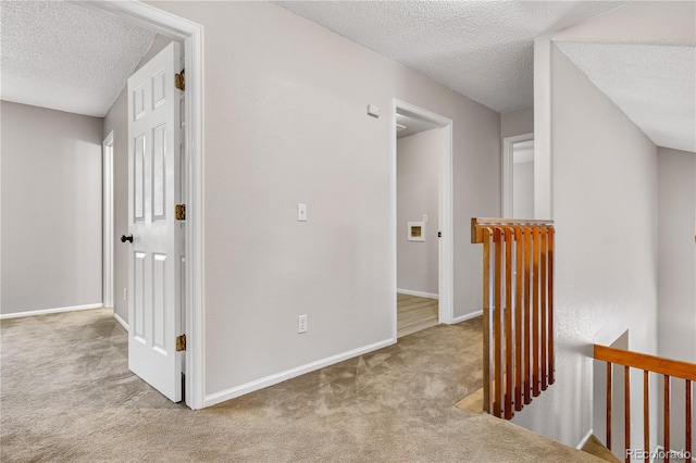 hallway with light carpet and a textured ceiling