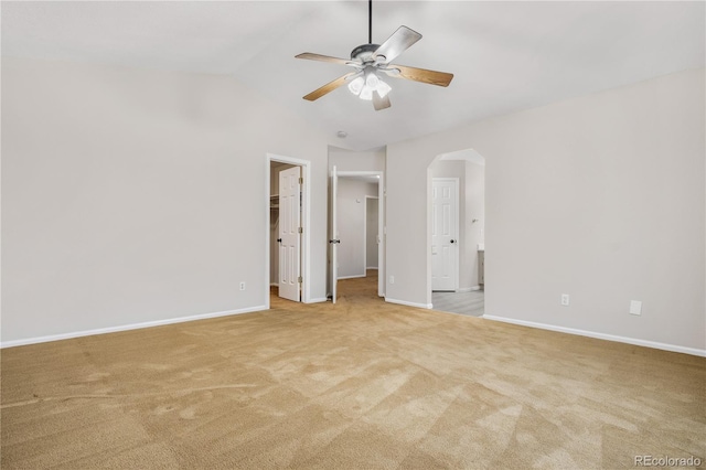 unfurnished bedroom with lofted ceiling, a walk in closet, ceiling fan, light carpet, and a closet