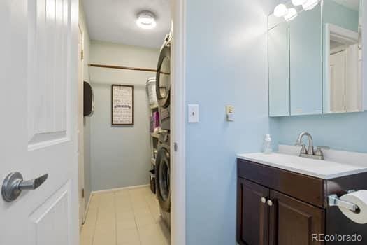 bathroom featuring stacked washer / dryer and vanity