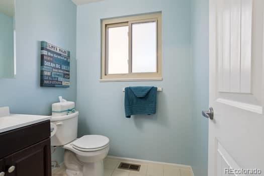 bathroom featuring baseboards, visible vents, vanity, and toilet