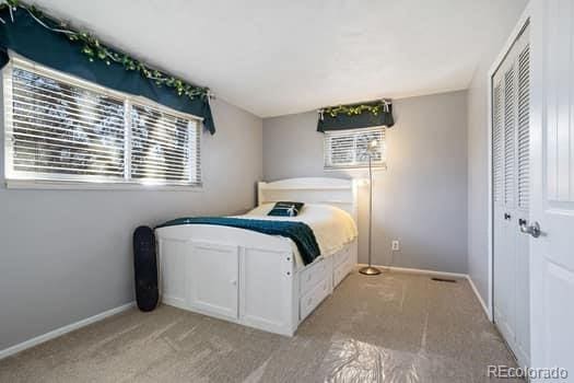 bedroom with a closet, light carpet, and baseboards