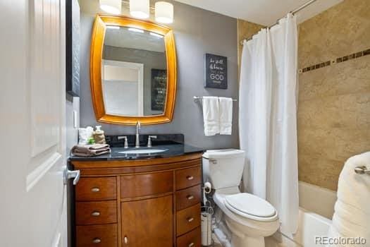 bathroom with toilet, shower / bath combination with curtain, and vanity