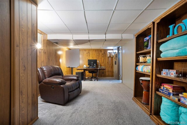 sitting room with a paneled ceiling, wood walls, and carpet flooring