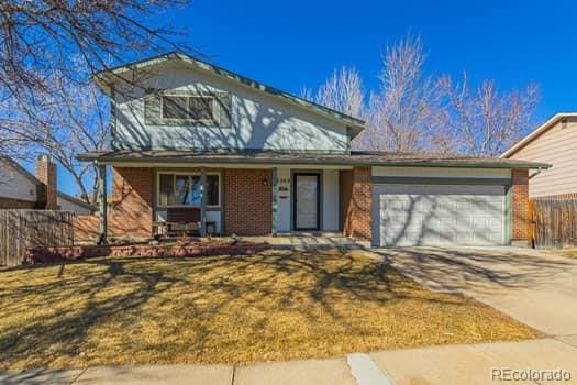 traditional-style house featuring concrete driveway, an attached garage, covered porch, fence, and brick siding