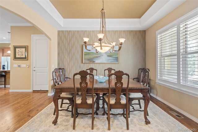 10182 Bristleridge St, Parker, CO 80134 - dining room featuring arched walkways, wood finished floors, a chandelier, baseboards, and crown molding