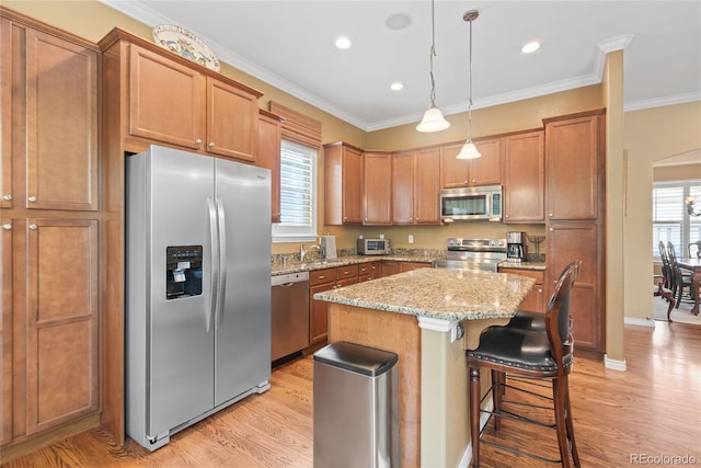 10182 Bristleridge St, Parker, CO 80134 - kitchen featuring stainless steel appliances, light wood-style flooring, light stone counters, a kitchen island, and crown molding