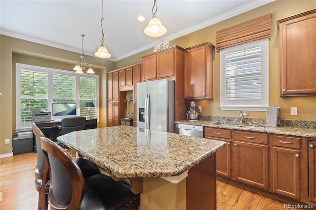10182 Bristleridge St, Parker, CO 80134 - kitchen with stainless steel appliances, a sink, light wood-type flooring, a center island, and brown cabinetry
