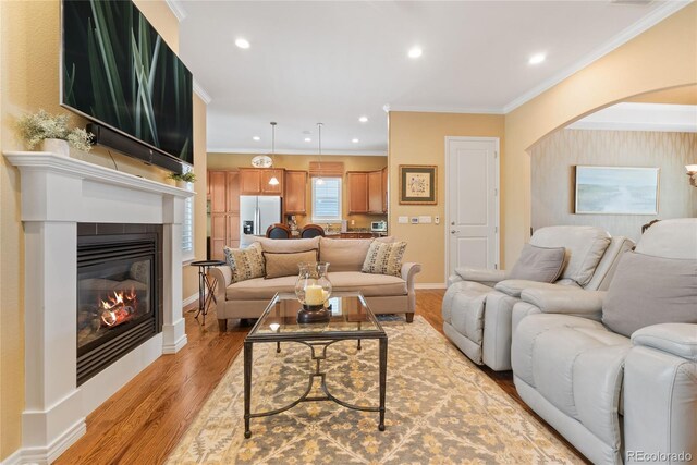 10182 Bristleridge St, Parker, CO 80134 - living area with crown molding, a glass covered fireplace, light wood finished floors, recessed lighting, and arched walkways