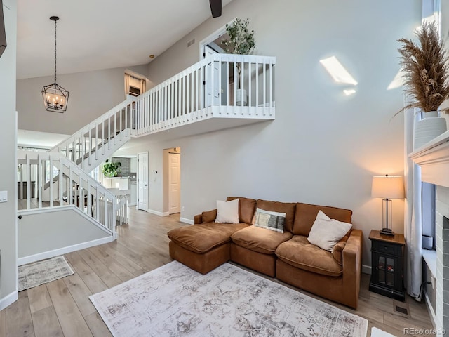 living room featuring a notable chandelier, light hardwood / wood-style floors, and high vaulted ceiling