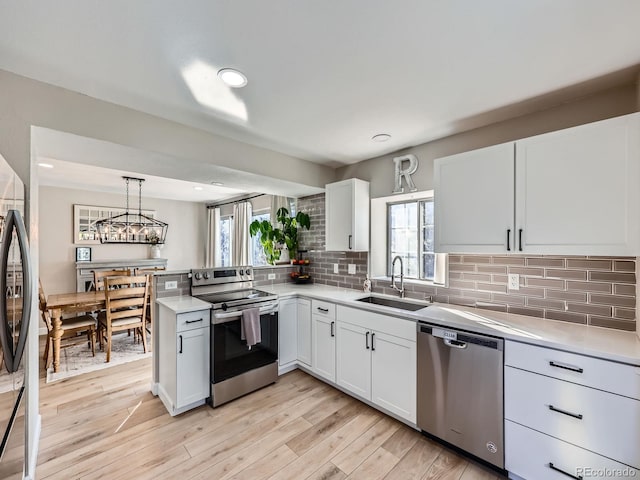 kitchen featuring appliances with stainless steel finishes, sink, pendant lighting, white cabinetry, and plenty of natural light